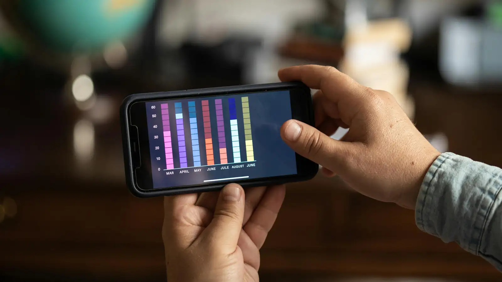 Hand holding phone with mobile app analytics dashboard